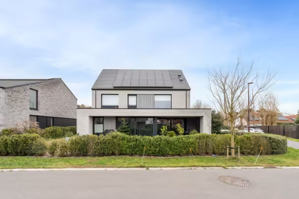 Voorgevel van moderne nieuwbouwwoning met brede raampartijen en voortuin, Hectaar woning