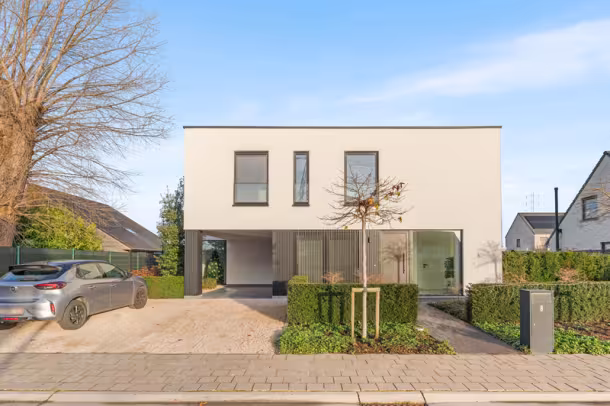 Voorgevel van moderne crepi Bouwen Op Maat nieuwbouwwoning met zwarte accenten in Roeselare