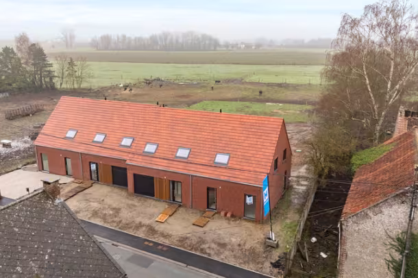 Luchtfoto van nieuwbouwproject met bakstenen woningen en rood hellend dak in landelijke omgeving