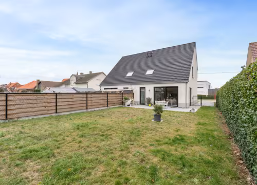 Achtertuin met terras en zicht op moderne woning met zadeldak, Hectaar realisatie in De Haan