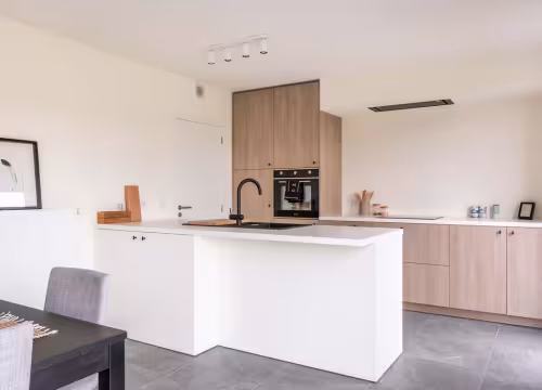Moderne keuken met eiland en houten kastenwand in een Hectaar nieuwbouwwoning