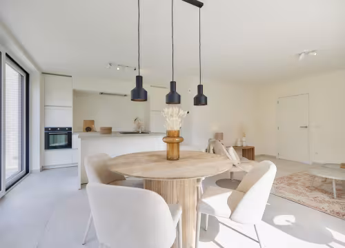 Eethoek met ronde tafel en hanglampen in nieuwbouwwoning in Bredene