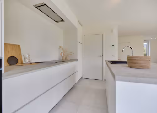 Strakke witte keuken met lange kastenwand