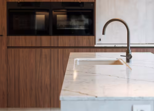 Moderne maatwerkkeuken in nieuwbouwwoning met marmerlook eiland en houten kasten