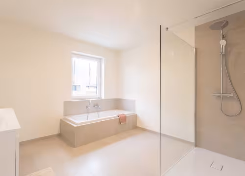 Ruime badkamer in nieuwbouwwoning met ligbad, wastafel en natuurlijke lichtinval