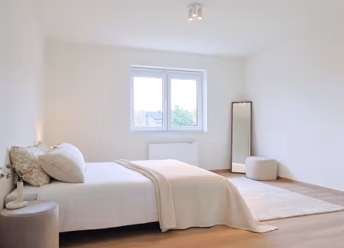 Ingerichte slaapkamer in moderne nieuwbouwwoning met houten vloer en veel lichtinval