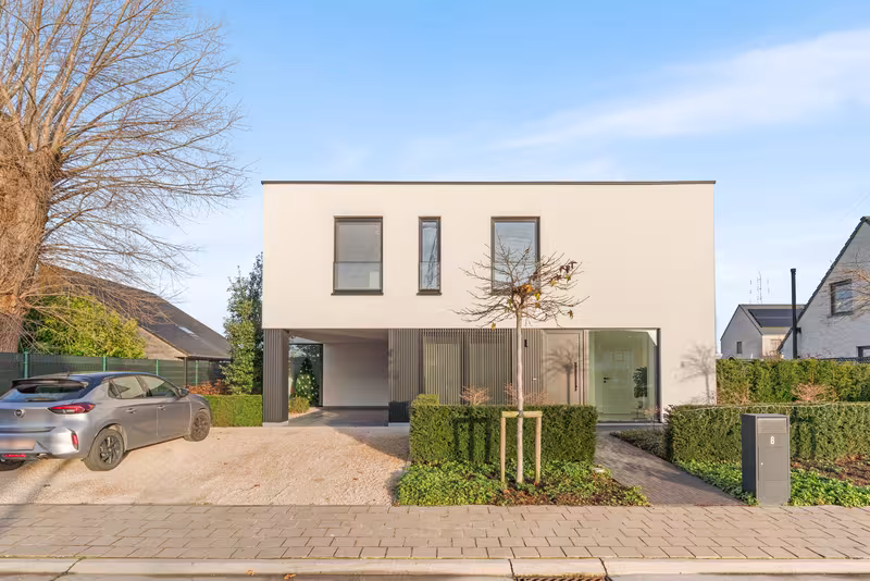 Voorgevel van moderne crepi Bouwen Op Maat nieuwbouwwoning met zwarte accenten in Roeselare